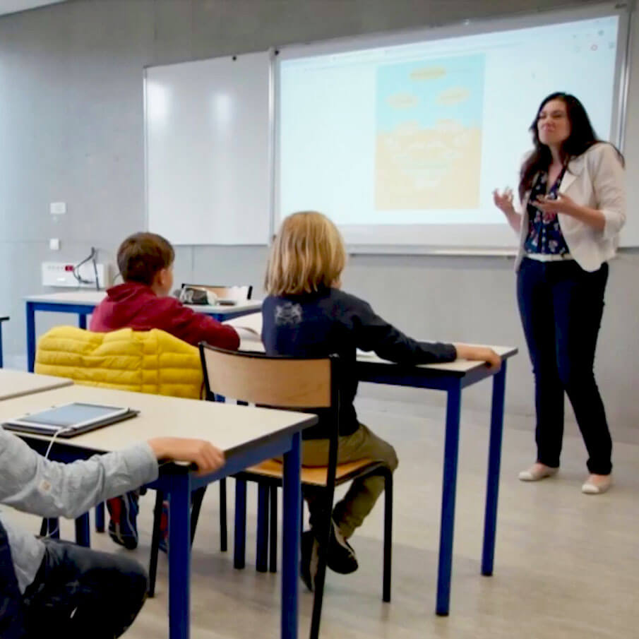L'image représente une salle de classe avec deux élèves et une enseignante.